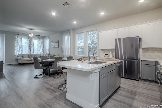 kitchen featuring tasteful backsplash, stainless steel appliances, a kitchen island with sink, sink, and light hardwood / wood-style floors