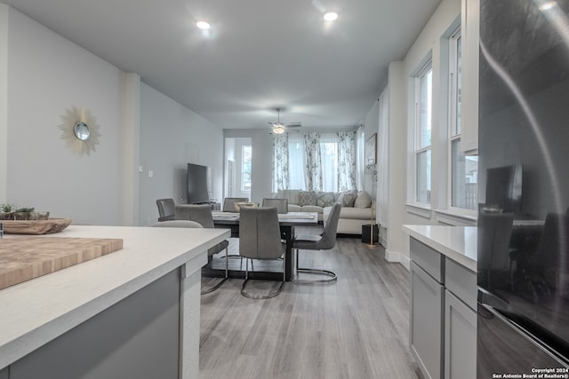 kitchen featuring gray cabinets, ceiling fan, black refrigerator, and light hardwood / wood-style flooring