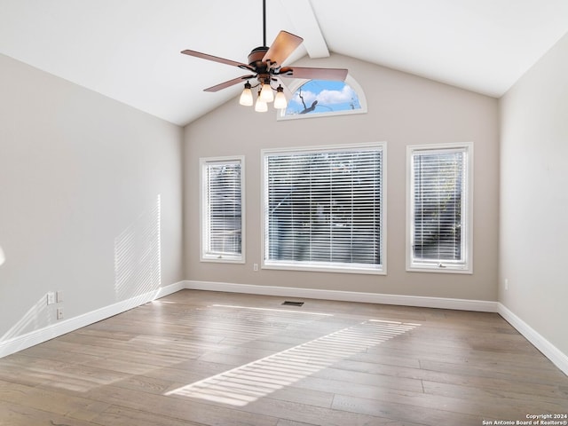 empty room with lofted ceiling with beams, light hardwood / wood-style floors, and a healthy amount of sunlight