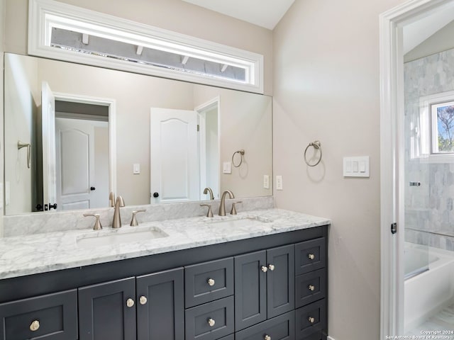 bathroom with vanity, lofted ceiling, and tiled shower / bath