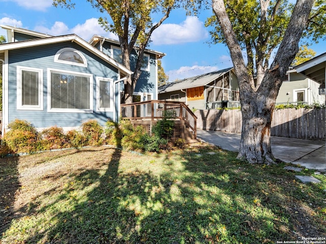 view of front of house featuring a wooden deck, a patio, and a front yard