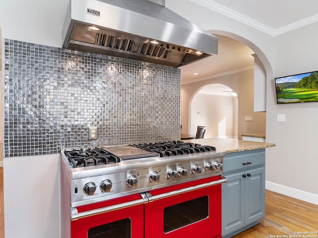 kitchen with wall chimney exhaust hood, backsplash, double oven range, light wood-type flooring, and ornamental molding