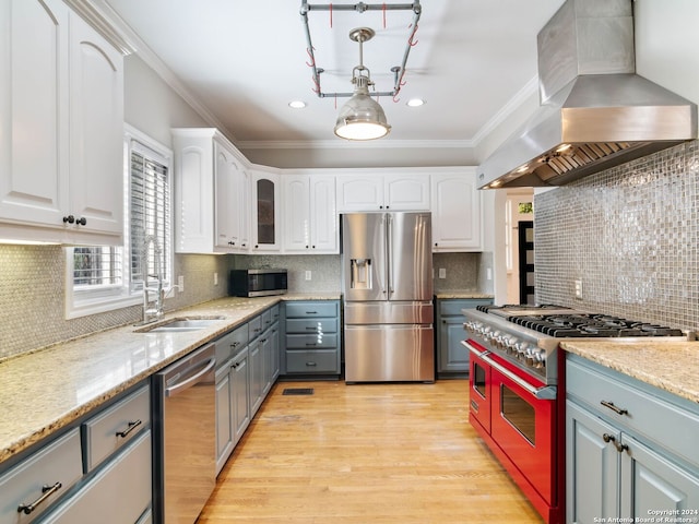 kitchen with decorative backsplash, appliances with stainless steel finishes, white cabinetry, and wall chimney exhaust hood