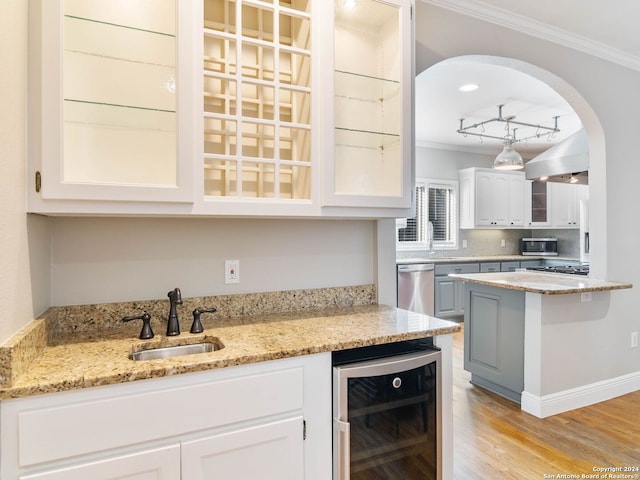 kitchen featuring white cabinets, wine cooler, light stone countertops, and sink