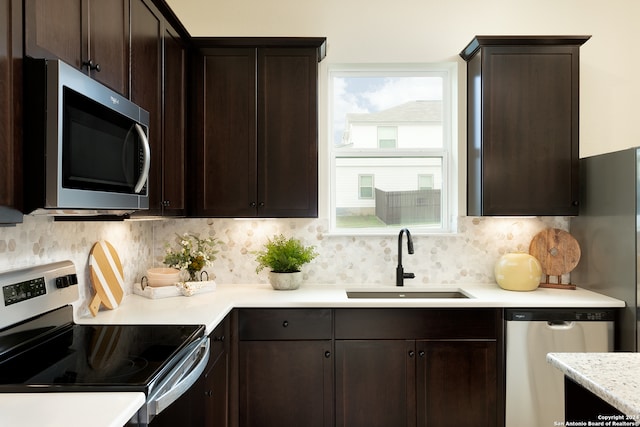 kitchen with tasteful backsplash, sink, dark brown cabinets, and appliances with stainless steel finishes