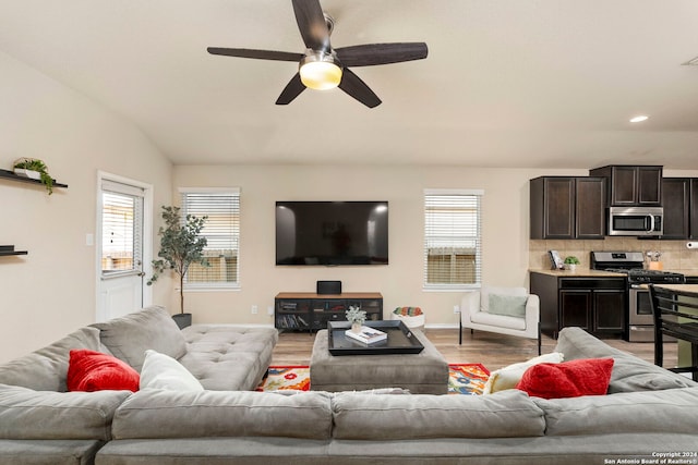 living room with ceiling fan, wood-type flooring, and vaulted ceiling