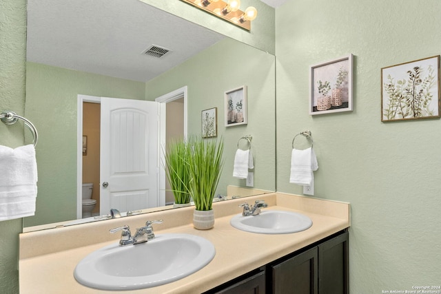 bathroom featuring a textured ceiling, vanity, and toilet