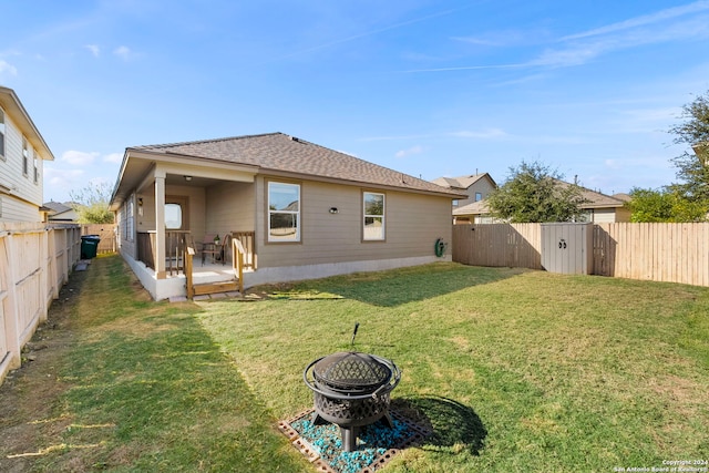 rear view of house featuring a fire pit, a deck, and a yard