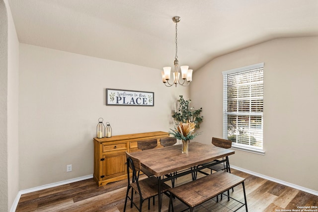 dining room with a notable chandelier, dark wood-type flooring, and vaulted ceiling