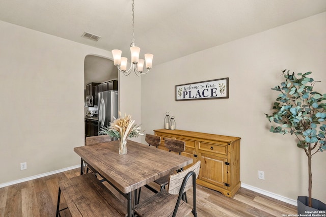 dining space with light hardwood / wood-style floors and an inviting chandelier