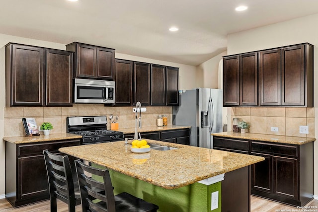 kitchen featuring dark brown cabinets, stainless steel appliances, a breakfast bar area, and an island with sink