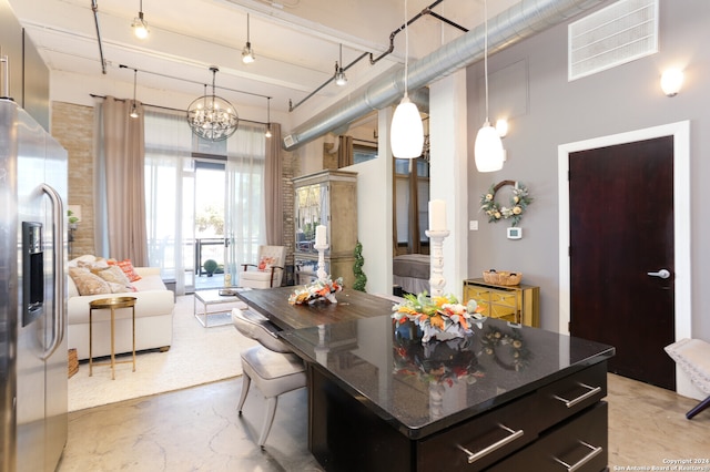 kitchen with stainless steel fridge, dark stone counters, decorative light fixtures, a notable chandelier, and a kitchen island