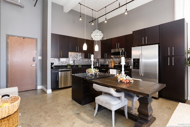 kitchen featuring dark brown cabinetry, hanging light fixtures, stainless steel appliances, a towering ceiling, and decorative backsplash