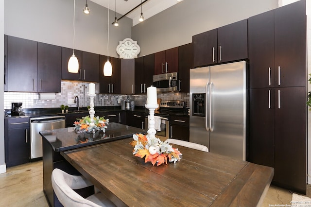 kitchen featuring hanging light fixtures, stainless steel appliances, a high ceiling, decorative backsplash, and dark brown cabinets