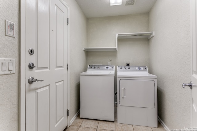 laundry room with light tile patterned floors and washer and clothes dryer