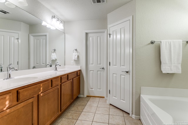 bathroom featuring a textured ceiling, vanity, tile patterned floors, and a bathing tub