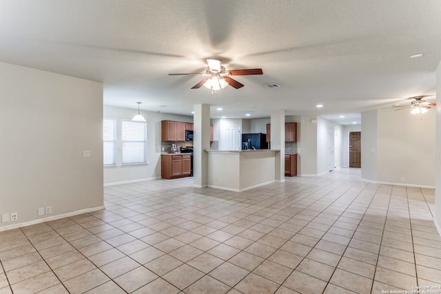 unfurnished living room featuring ceiling fan, light tile patterned floors, and a textured ceiling