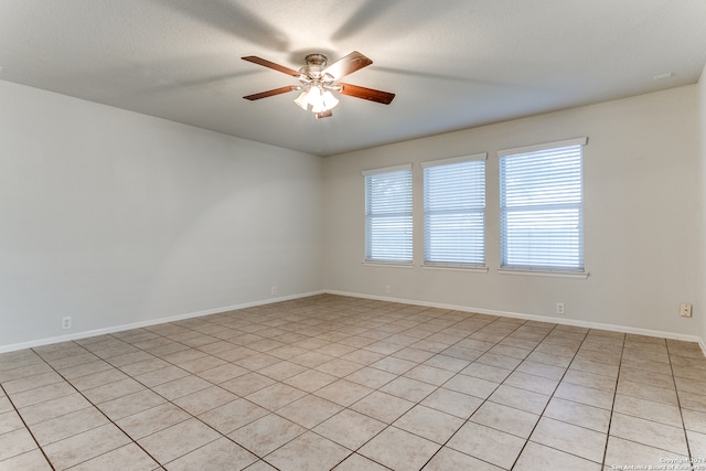 spare room featuring ceiling fan, light tile patterned floors, and a textured ceiling