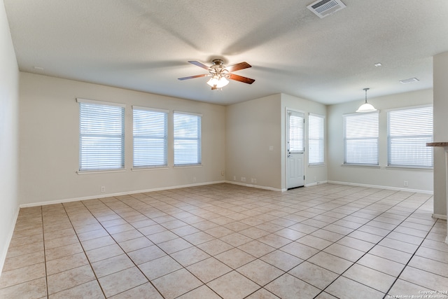 spare room with ceiling fan, a textured ceiling, a wealth of natural light, and light tile patterned flooring