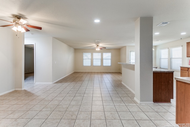 unfurnished living room featuring plenty of natural light, ceiling fan, and light tile patterned floors