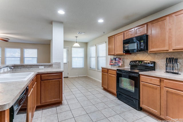 kitchen with tasteful backsplash, sink, black appliances, hanging light fixtures, and light tile patterned flooring