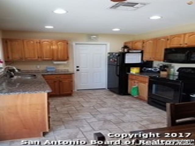 kitchen featuring black appliances, sink, and dark stone counters