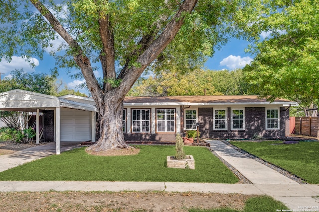 single story home with a front lawn, a carport, and a garage