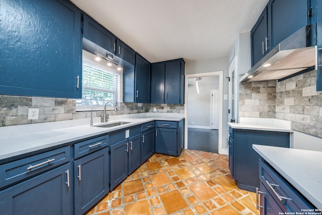 kitchen featuring decorative backsplash, sink, range hood, and blue cabinets