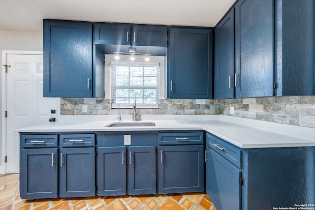 kitchen featuring backsplash, blue cabinetry, and sink