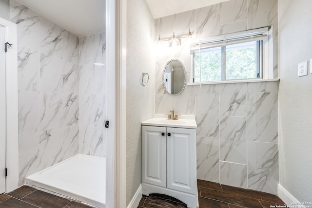 bathroom featuring a tile shower, vanity, and wood-type flooring