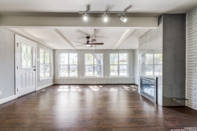 unfurnished living room with ceiling fan, brick wall, dark hardwood / wood-style floors, and a brick fireplace