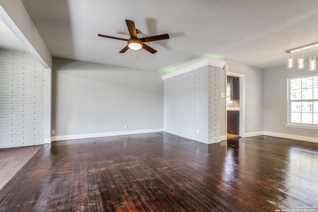 unfurnished living room featuring ceiling fan, dark hardwood / wood-style flooring, and brick wall