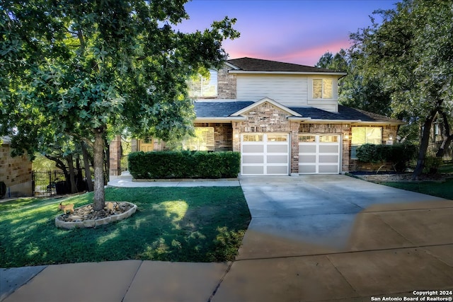 view of front of house with brick siding, concrete driveway, a lawn, fence, and a garage