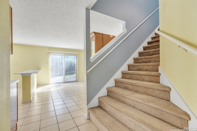 stairway featuring a textured ceiling and tile patterned floors