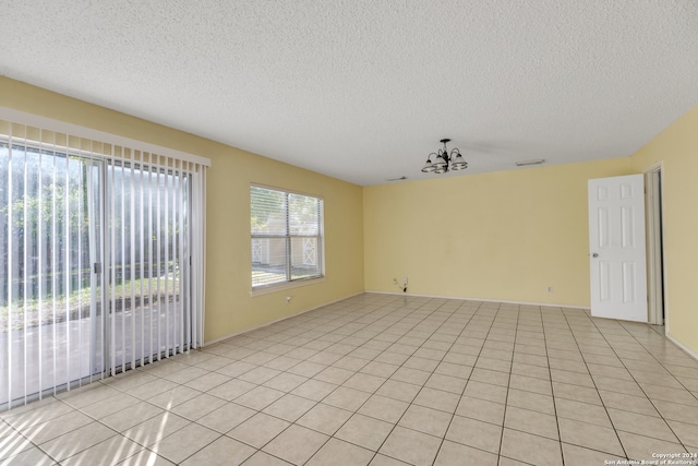 unfurnished room with a notable chandelier, light tile patterned floors, and a textured ceiling