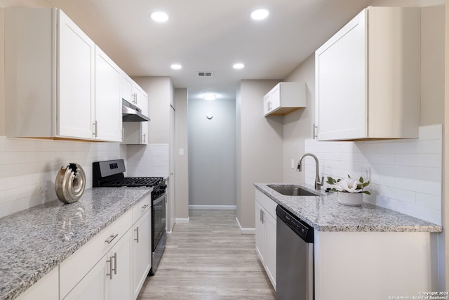 kitchen featuring white cabinets, appliances with stainless steel finishes, light stone counters, and sink