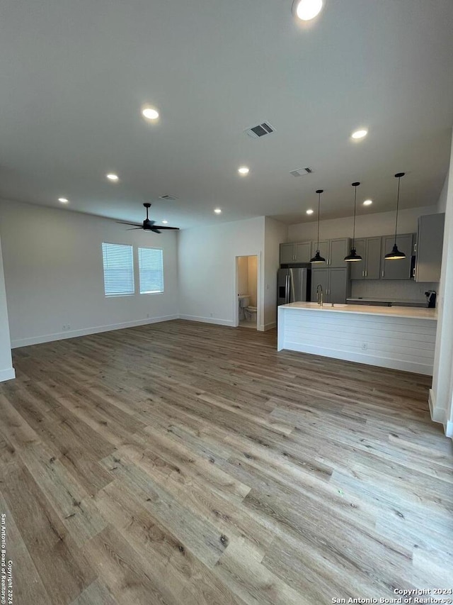 kitchen featuring gray cabinetry, stainless steel fridge, ceiling fan, and light hardwood / wood-style floors