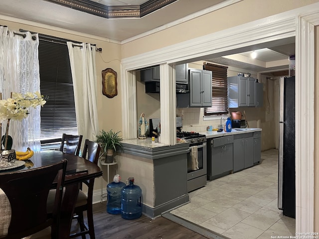 kitchen with decorative backsplash, appliances with stainless steel finishes, ornamental molding, light hardwood / wood-style floors, and gray cabinets