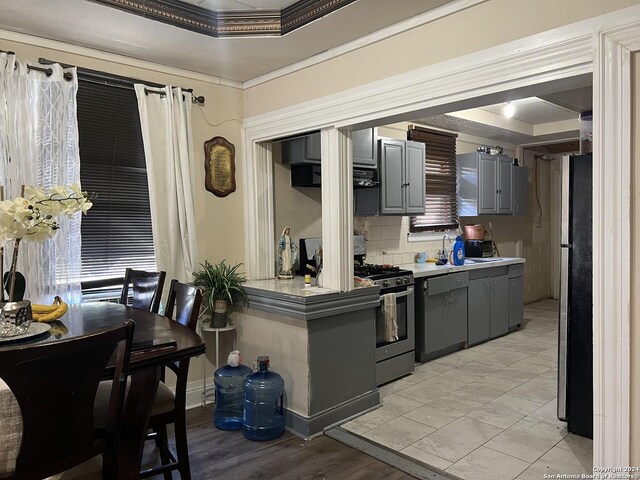 615 Carolina St, San Antonio, TX 78210 - kitchen with gray cabinetry, a raised ceiling, stainless steel appliances, backsplash, and crown molding