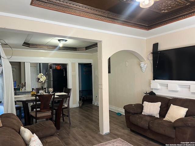 living room with a raised ceiling, crown molding, and dark wood-type flooring