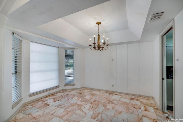 unfurnished dining area featuring a chandelier and a tray ceiling