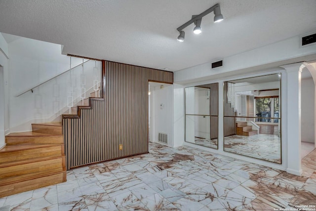 interior space featuring a textured ceiling and wooden walls