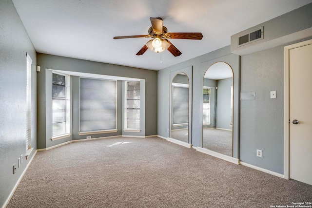 unfurnished room featuring carpet, a wealth of natural light, and ceiling fan