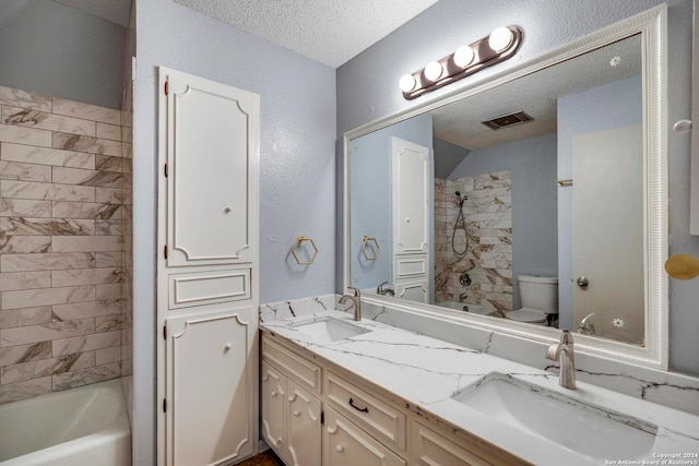 full bathroom featuring vanity, tiled shower / bath combo, a textured ceiling, and toilet