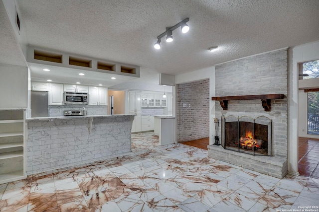 kitchen featuring kitchen peninsula, white cabinetry, a textured ceiling, and appliances with stainless steel finishes