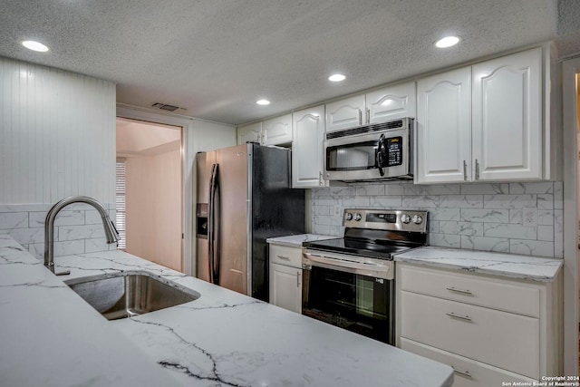 kitchen featuring white cabinets, appliances with stainless steel finishes, a textured ceiling, and sink