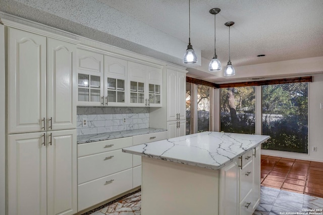 kitchen with a center island, white cabinetry, hanging light fixtures, and backsplash