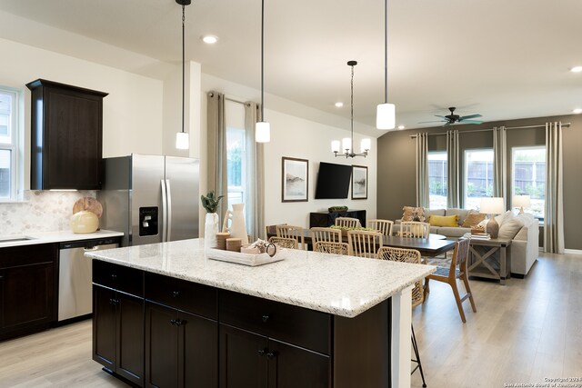 kitchen with pendant lighting, a kitchen island, appliances with stainless steel finishes, light hardwood / wood-style floors, and a breakfast bar area