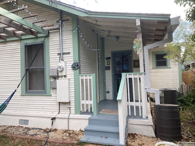 property entrance with central air condition unit, a pergola, and covered porch