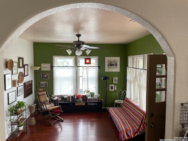 living area featuring ceiling fan, wood-type flooring, and a textured ceiling